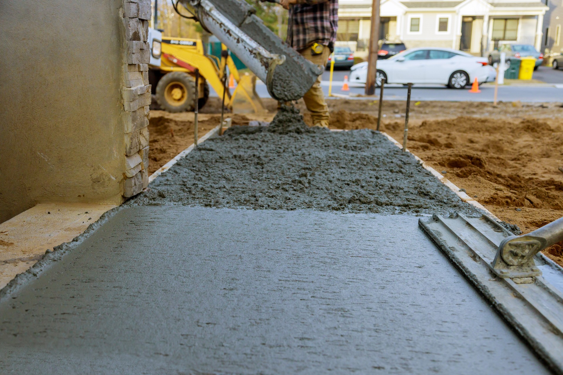 Construction worker pour cement for sidewalk in new residential home